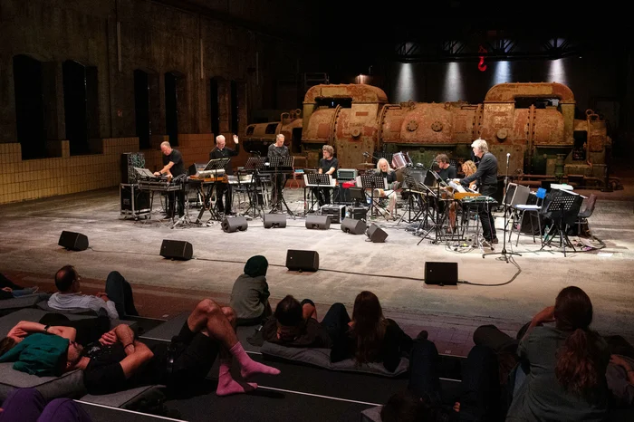 An ensemble of musicians with electronic instruments on stage.