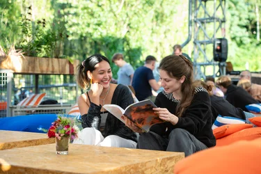 Zwei Besucherinnen, die auf Sitzsäcken sitzen und eine Programmbroschüre der Ruhrtriennale lesen.