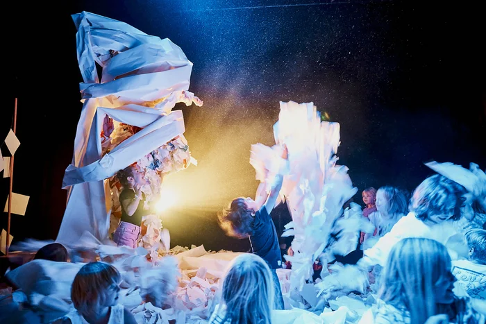 Performer:innen in Papier eingewickelt, umgeben von Kindern und Erwachsenen