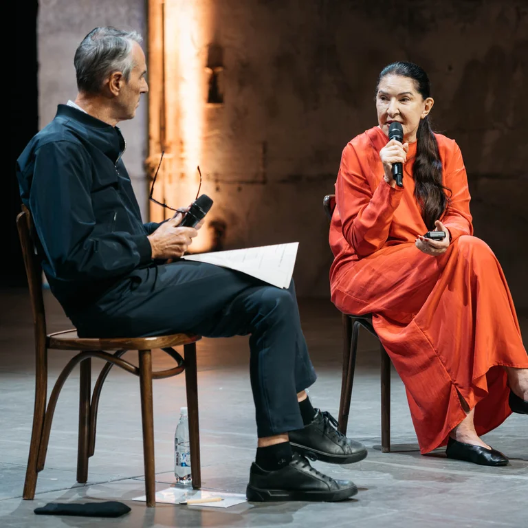 Artistic Director Ivo Van Hove and Marina Abramović are sitting on stage, facing each other.
