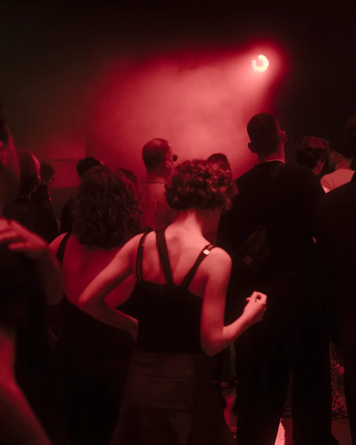 People are dancing and standing in red light and haze in the Jahrhunderthalle in Bochum.
