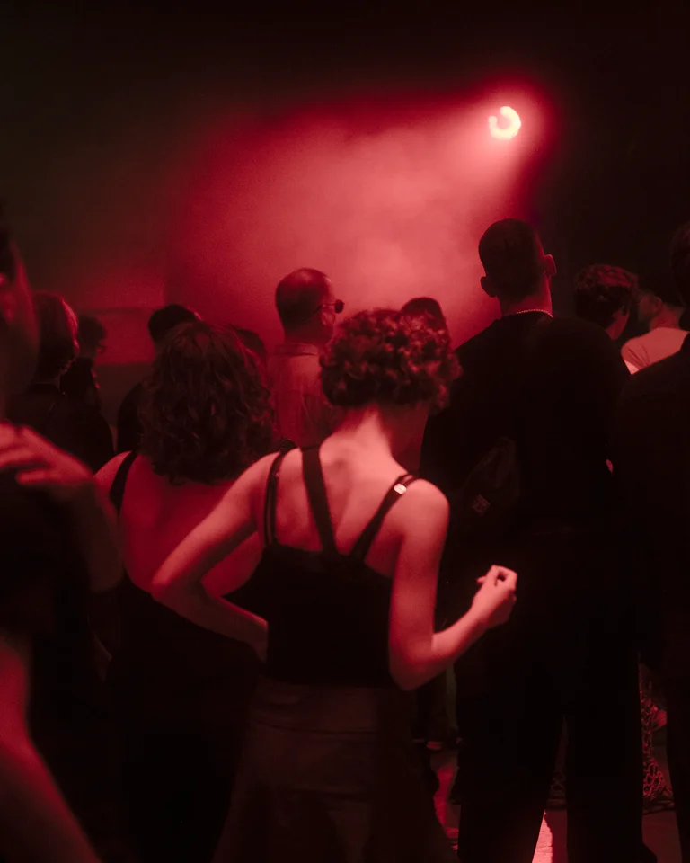 People are dancing and standing in red light and haze in the Jahrhunderthalle in Bochum.