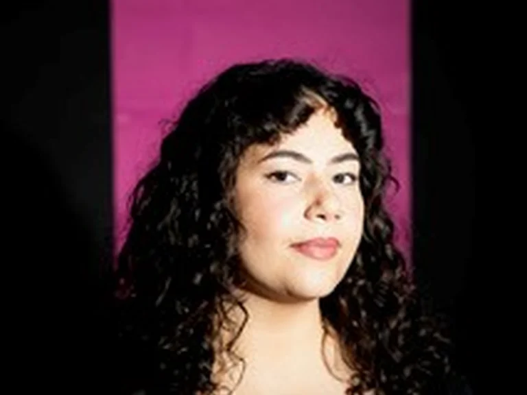 Portrait von Nada Ftouni vor pinkem Hintergrund, halbseitig zur Kamera gewandt