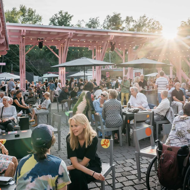 Großes Publikum im Festivalzentrum Wunderland, das sich bei strahlendem Sonnenschein angeregt unterhält.