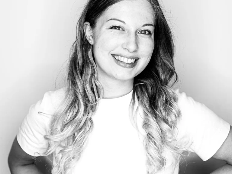 Portrait von Reemda Hahn, Hände in die Hüften gestützt, vor hellem Hintergrund.