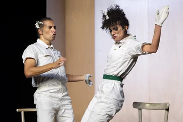 Marlene Monteiro Freitas und Israel Galván stehen sich in weißen Overalls tanzend gegenüber; Monteiro Freitas hebt den Arm, Galván lehnt sich seitlich zurück.