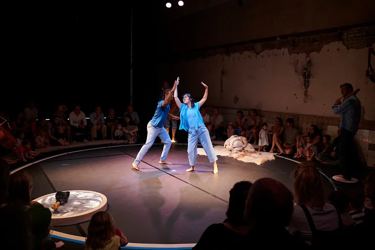 Zwei Tänzer:innen des Ensembles in der Mitte der Bühne. Das Licht ist auf sie gerichtet. Das Stück "Little Ears, Tiny Feet" wird im Dampfgebläsehaus in Bochum aufgeführt