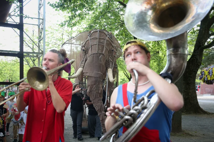 Two people with trumpets in front of a life-size elephant figure as part of the ‘Celebration Parade’