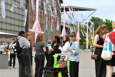 A group of young people stands in front of a colorful installation with the sign "Teens Talk." One participant smiles at the camera.