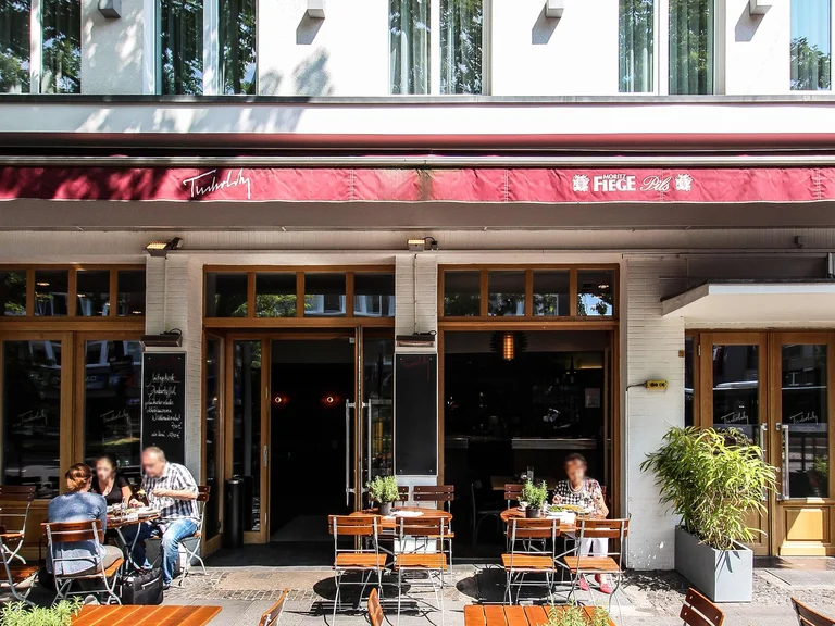 Exterior view of the art Hotel Tucholsky in Bochum with a street café and guests on the terrace during daytime.