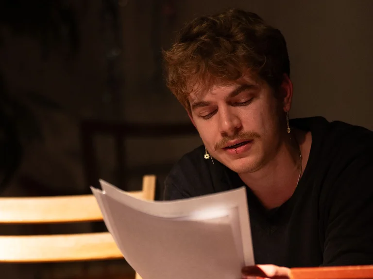 Emrys Perera is holding several A4 sheets of paper, from which he is reading.