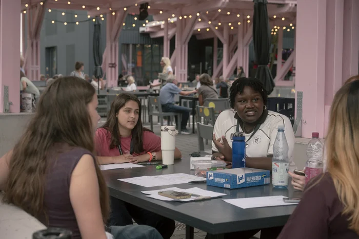 A group of young people sit around a table and talk together at the festival centre.