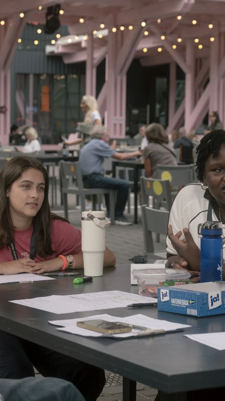 A group of young people sit around a table and talk together at the festival centre.