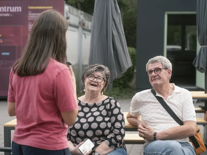 A young woman talks to two seated visitors at the Ruhrtriennale festival centre.