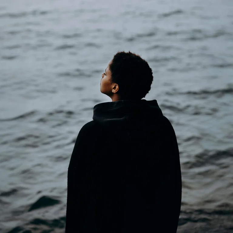 Singer-Songwriterin Meskerem Mees fotografiert von hinten, auf Wasser schauend.