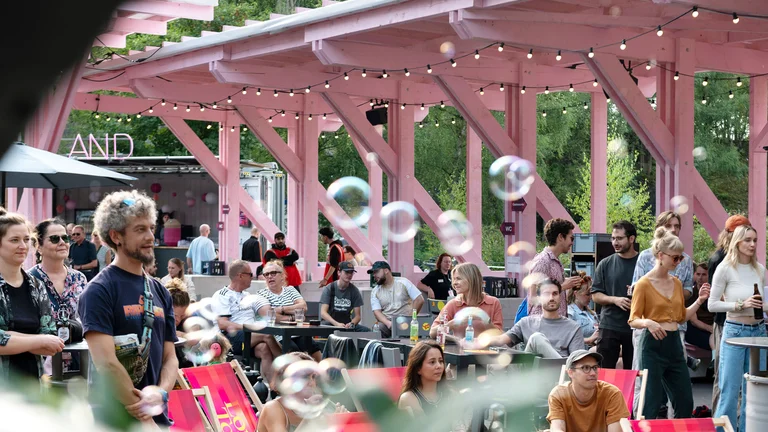 People are standing or sitting relaxed in the Wunderland festival centre, with soap bubbles floating through the air.