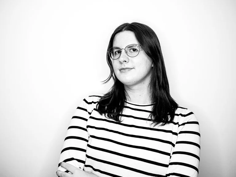 Lea Groher steht mit verschränkten Armen vor hellem Hintergrund.