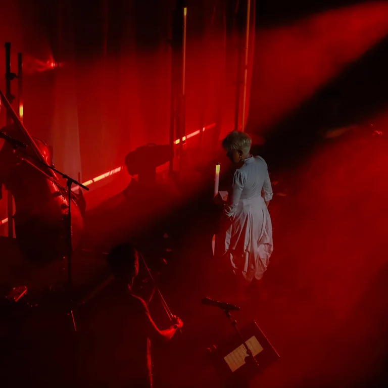 JoyceDiDonato und die drei Musiker von Time for Three stehen auf einer dramatisch rot beleuchteten Bühne.