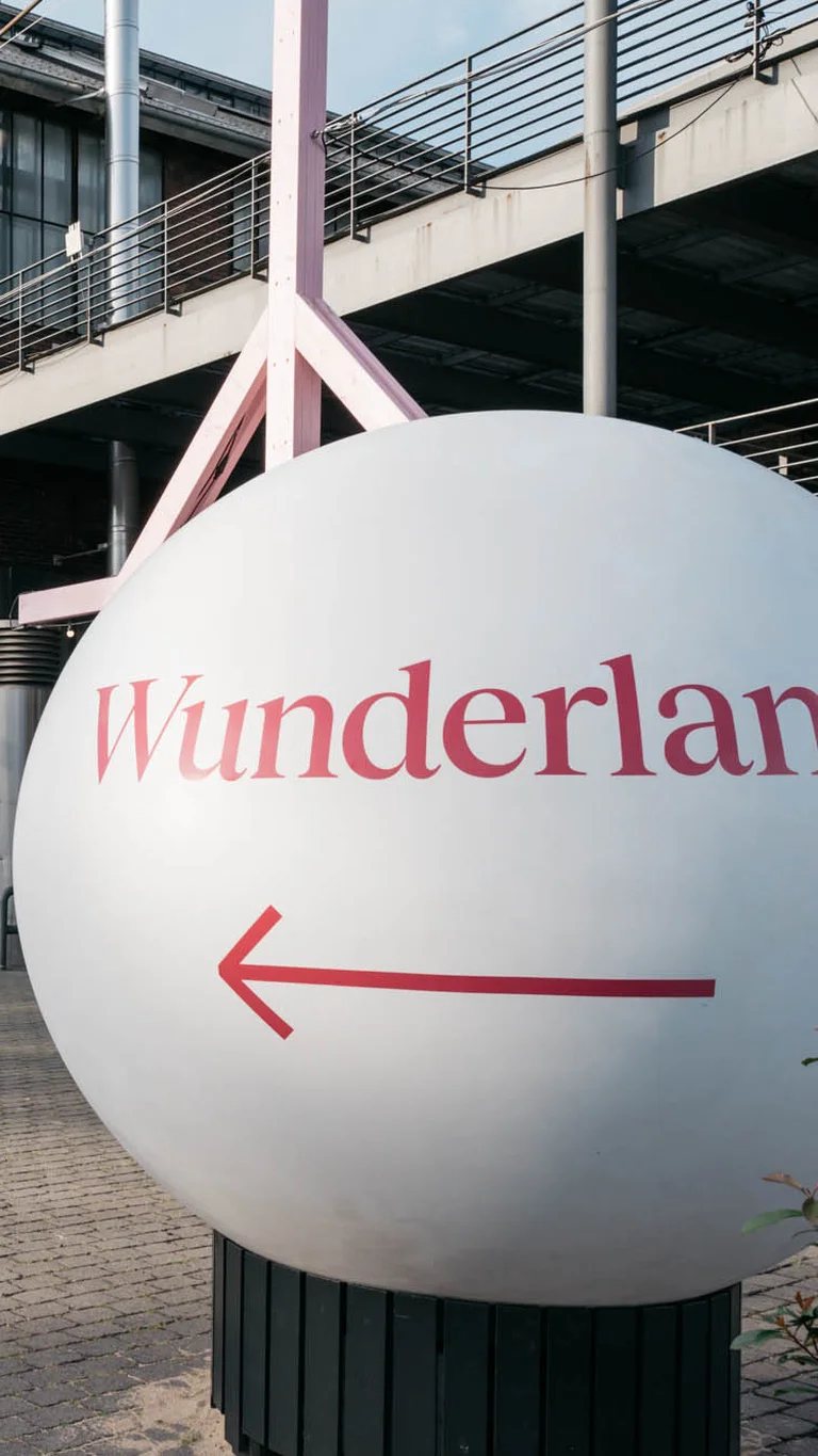 Eine große weiße Kugel mit der Aufschrift "Wunderland" und einem Pfeil deutet den Weg zum Festivalzentrum der Ruhrtriennale, vorbei an der Jahrhunderthalle Bochum.