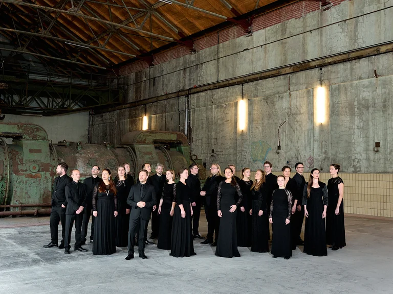 The Chorwerk Ruhr ensemble can be seen in the Turbinenhalle Bochum. The singers are dressed in black.