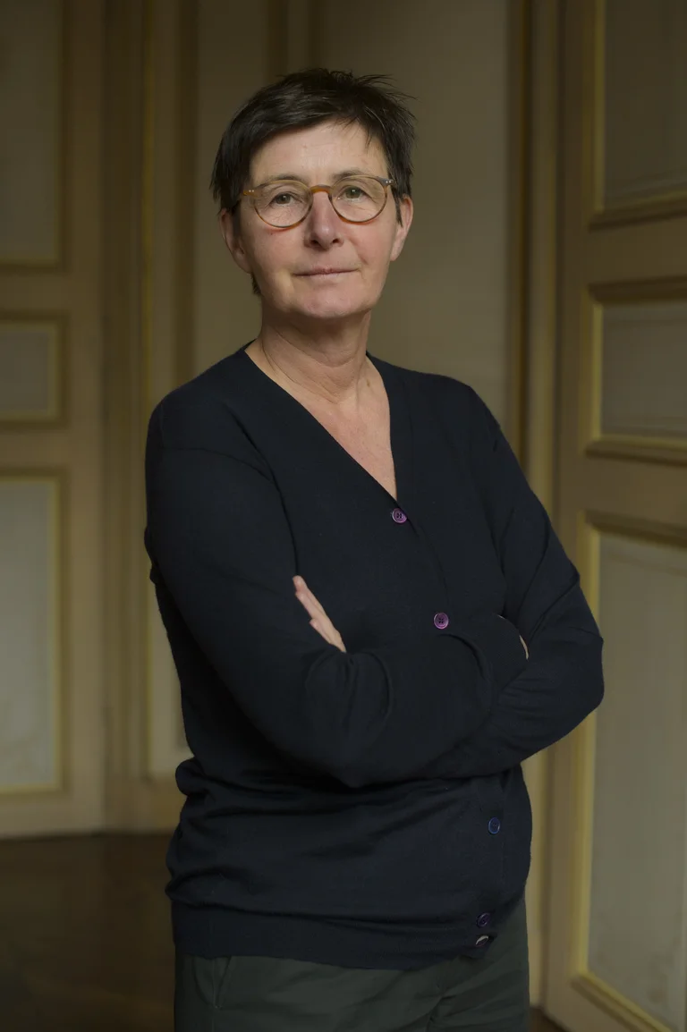 A woman in a dark top, the artist Berlinde De Bruyckere, looking into the camera