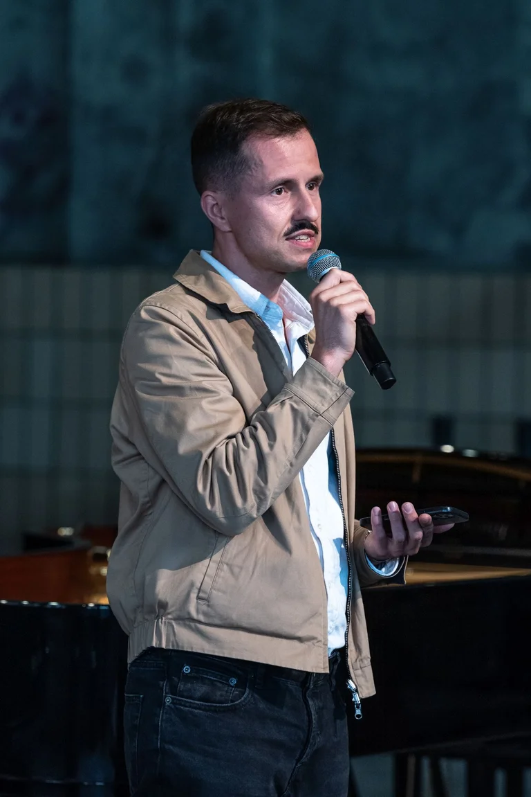 Krystian Lader on stage with a microphone in the Turbinenhalle in Bochum