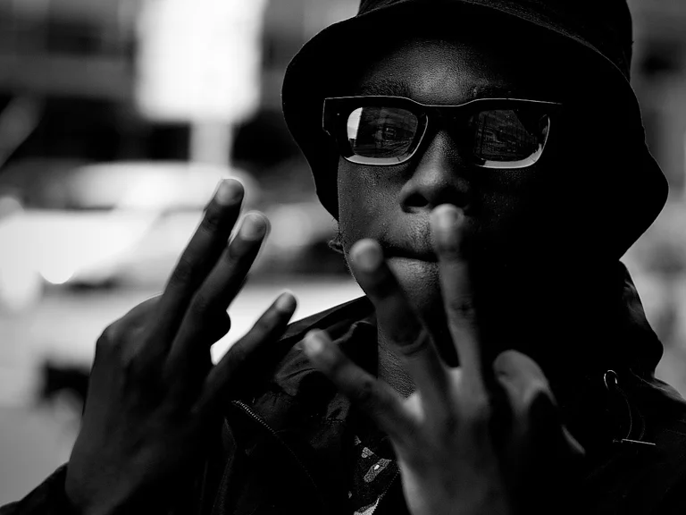 Black and white photograph of SLABBOY wearing sun glasses and a hat.