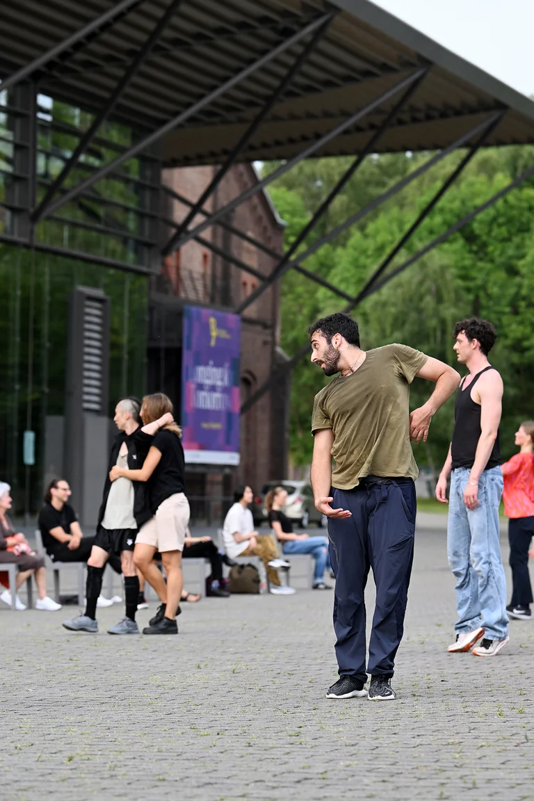 Ein Tänzer in grünem Shirt tanzt zum Publikum auf dem Vorplatz der Jahrhunderhalle in Bochum