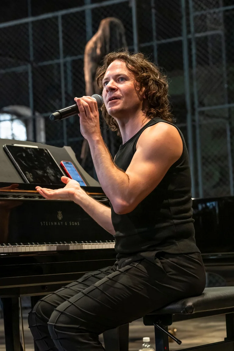 Richard Valitutto, a musician from the group ‘Wild Up’, sits at a piano with a microphone and speaks to the audience in the Turbinenhalle in Bochum