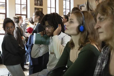 Besucher:innen einer Ausstellung hören über Kopfhörer einer Audioaufnahme zu.