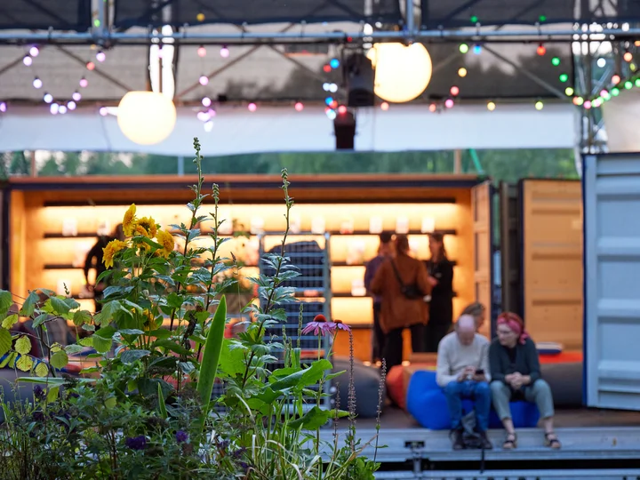 Photo of a plant in the poplar forest at the Jahrhunderthalle Bochum, people in an atmospheric event area in the background.