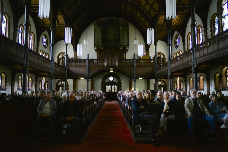 Interior of the Evangelical Church at the Market in Katernberg during the event 124 Years of Reverb. The high wooden ceilings, balconies, and the large organ dominate the space, while the pews are filled with attendees. Soft light filters through the stained-glass windows into the nave.