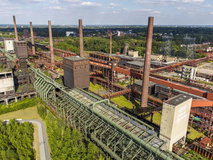 Aerial view of the Zollverein coking plant in Essen, showcasing its iconic chimneys and buildings surrounded by greenery.