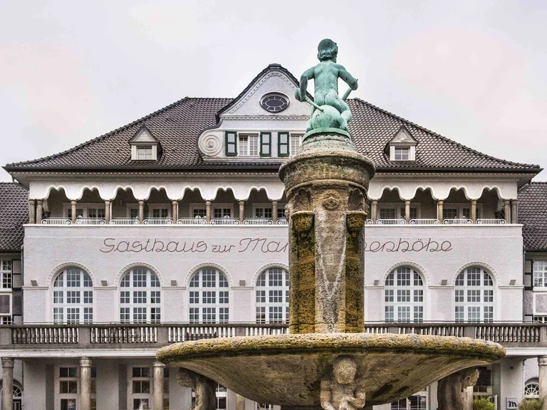 Historic building of the Mintrops Stadt Hotel Margarethenhöhe in Essen with a central fountain in the foreground.