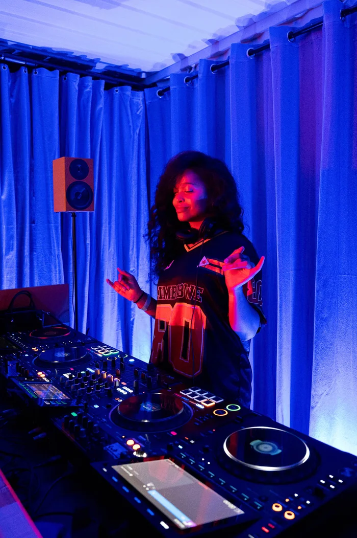 A DJ performs at a mixing desk in blue and red light at the Ruhrtriennale festival centre.