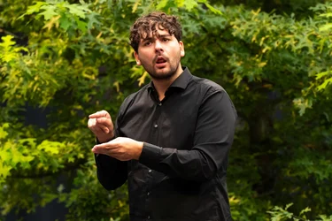 Dolmetscher Lars Grombelka übersetzt die Diskursveranstaltung "Brave New Voices" mit Autorin und Dramatikerin Sivan Ben Yshai bei der Ruhrtriennale 2024 in Deutsche Gebärdensprache.