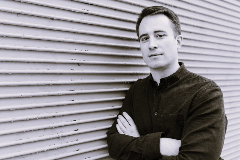 Man in black shirt, the director Ted Huffman, leaning against a wall