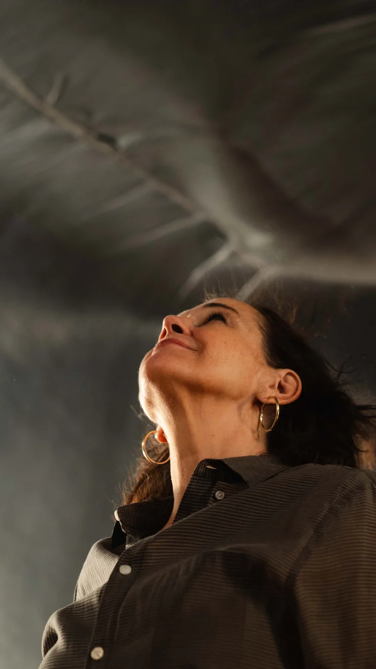 A person looks upward on a stage as a large translucent sheet billows overhead.