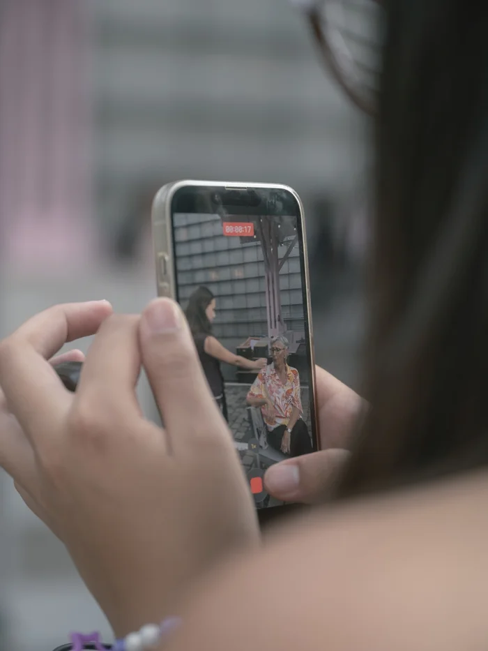 Close-up of a smartphone being used by a young person to record a conversation with a visitor.
