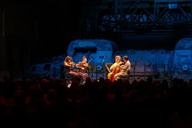 Das Attacca Quartet spielt vor einer blau beleuchteten Industriekulisse.
