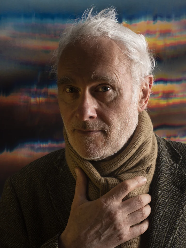 Man with scarf and jacket looks into the camera