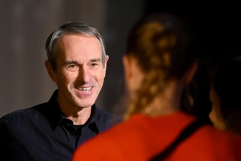 Ivo Van Hove smiles while talking to a person.