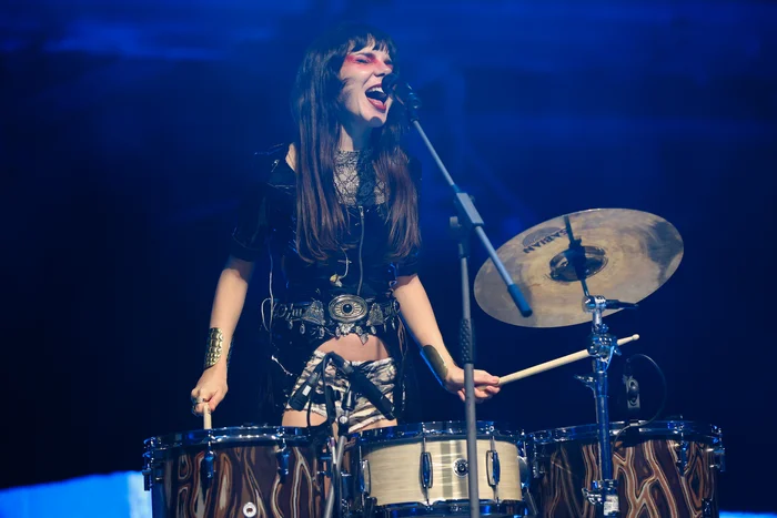 Gaye Su Akyol plays the drums and passionately sings into the microphone on stage.