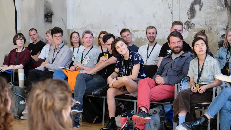 Students of the International Festival Campus sitting on chairs and looking spellbound to the right.