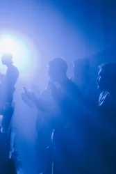 Menschen tanzen in diffusem, blauen Licht.