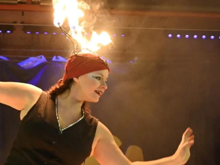 A person balances a flame on their head during a performance.