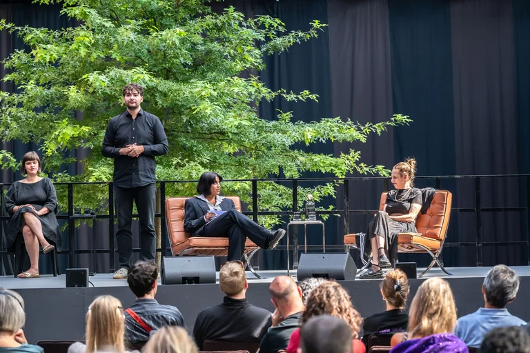 The audience in the foreground. A sign language interpreter, the presenter and Sivan Ben Yishai in the Jahrhunderthalle, Bochum