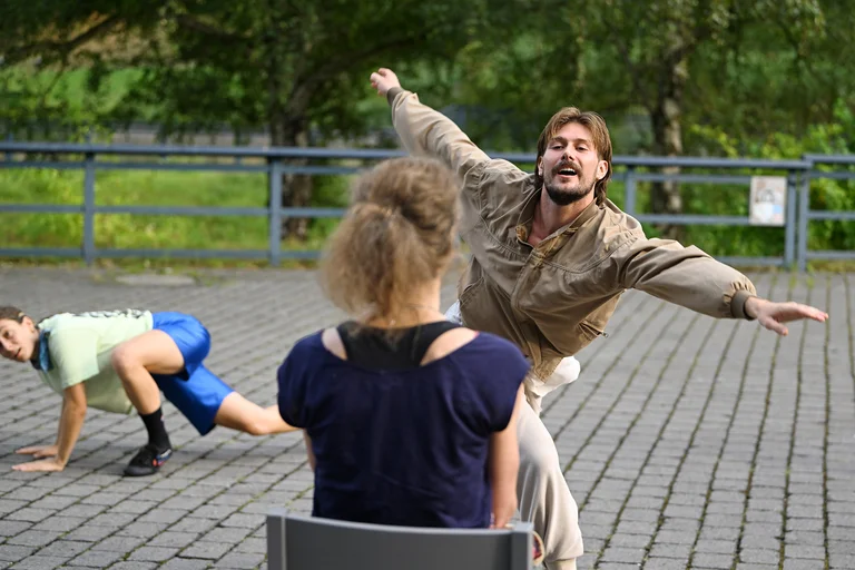 Ein Tänzer streckt die Arme weitaus und tanzt zu einer Person aus dem Publikum auf einem Stuhl