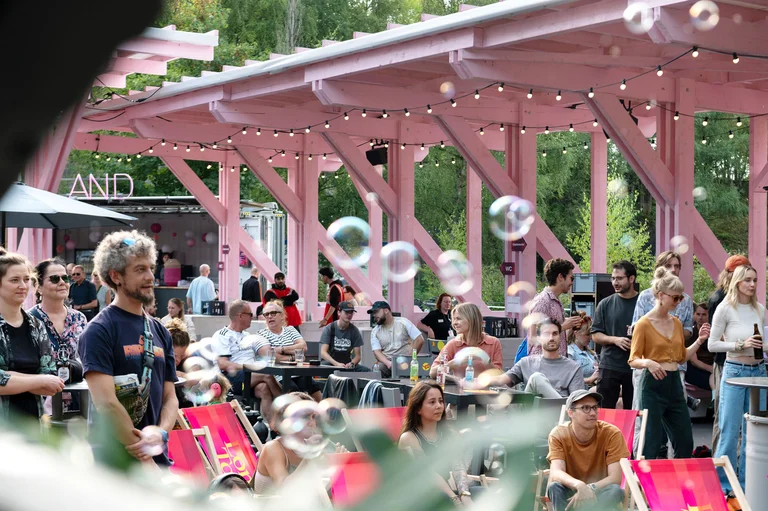 Publikum entspannt in Liegestühlen und unter rosa Pavillon bei sommerlicher Stimmung.