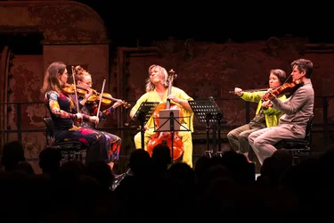 Caroline Shaw und das Attacca Quartet spielen vor warm beleuchteter Industriekulisse.